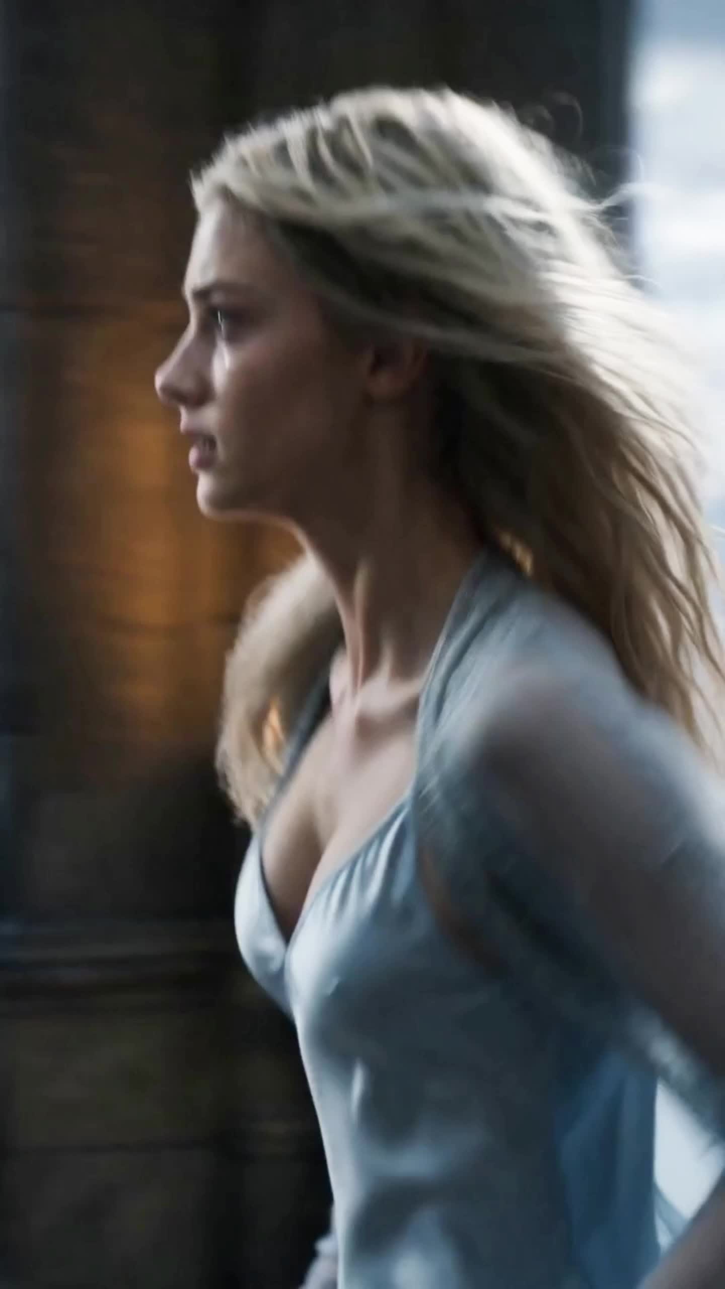 Cassia in profile, blonde hair blowing loose, in a pale blue dress, her face wet with tears and her eyes fixed ahead