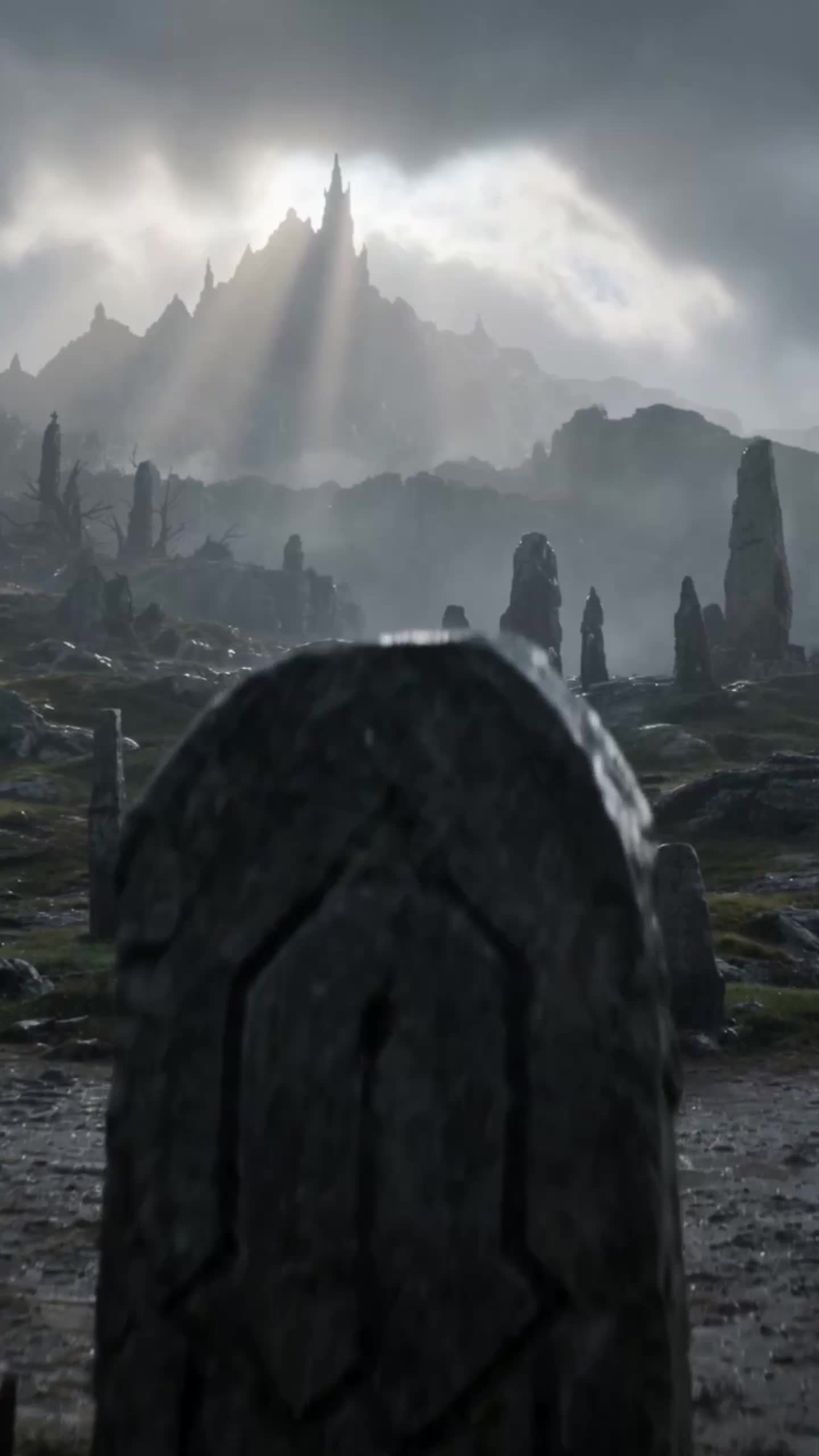 A carved stone grave marker in the foreground of a field of standing stones and dead trees, with a mountain of jagged spires lit by sunbeams through grey clouds behind