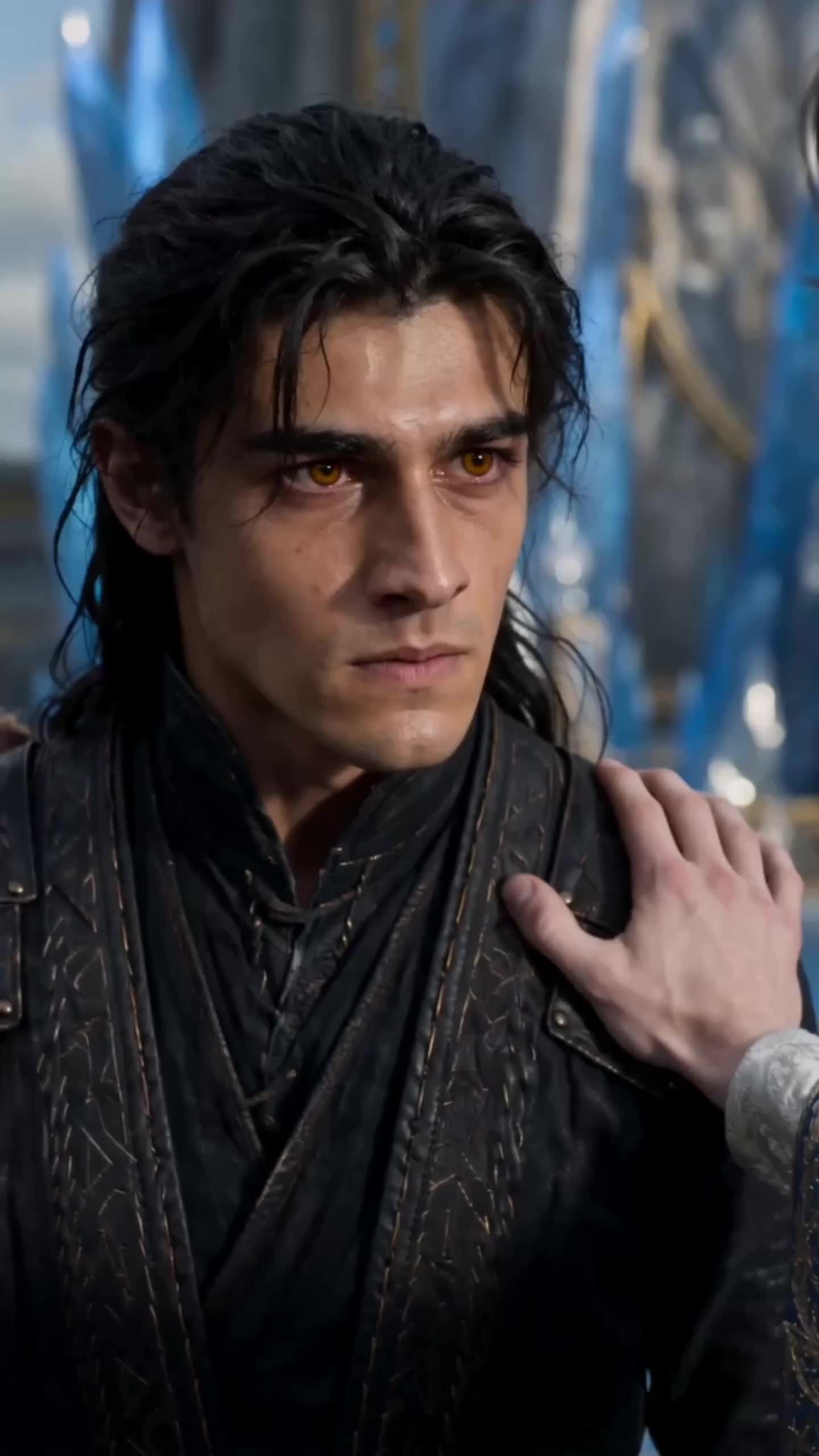 Cedric with long black hair and amber eyes, in a black leather coat, looking sideways while a hand from off-frame rests on his shoulder; blue crystal spires behind him